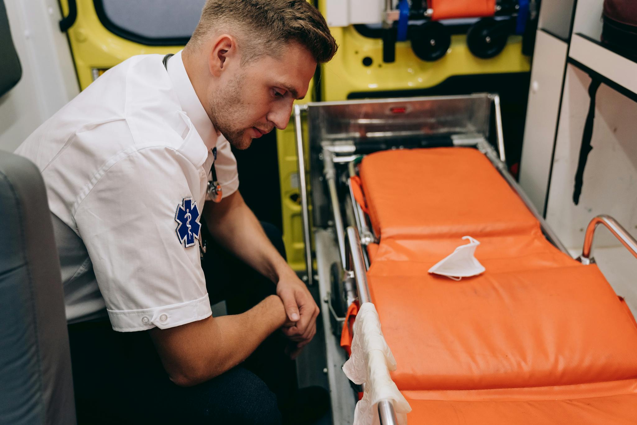 A paramedic prepares a stretcher inside an ambulance, focusing on readiness and professionalism.